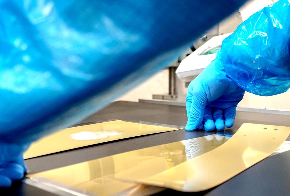 Gloved hands handling a gold sensor sheet